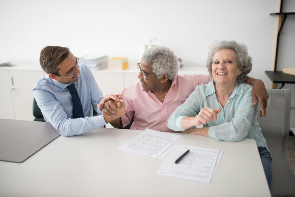 Older couple consulting with an advisor at a table, discussing funeral planning documents, conveying warmth and reassurance in a professional setting.