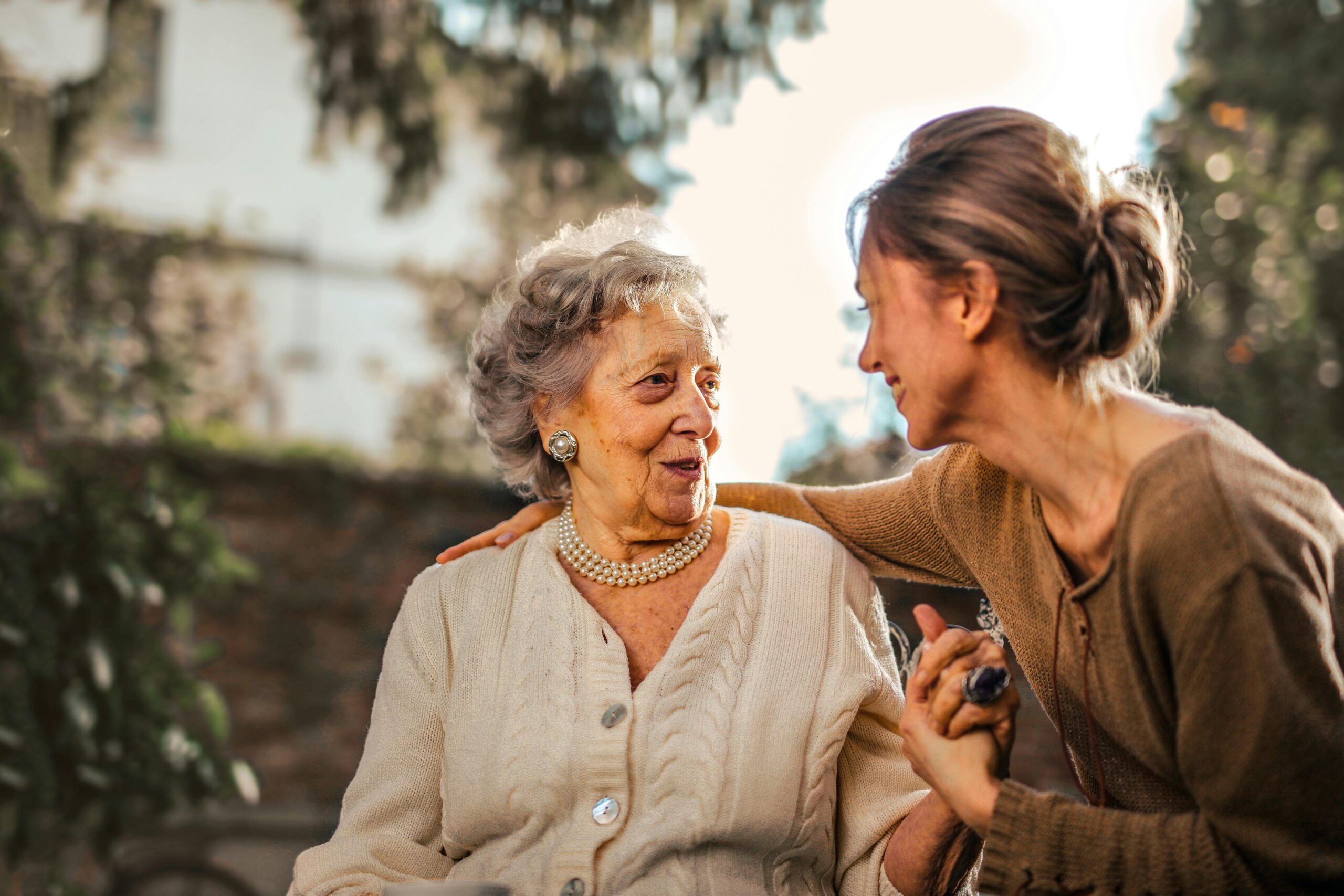 Elderly woman and younger woman smiling and engaging in conversation, representing family connection and support in planning for funeral insurance.