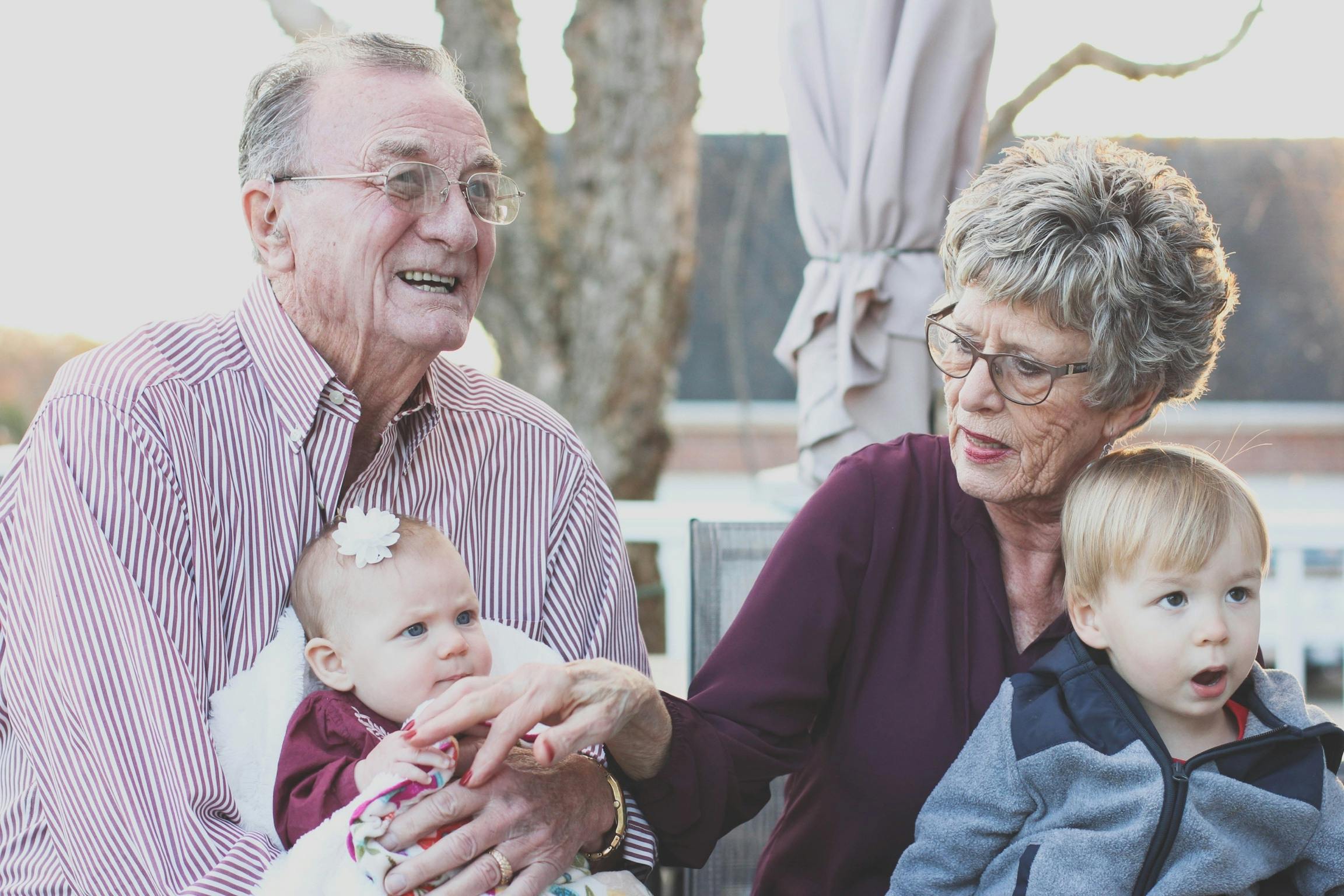 Elderly couple smiling and interacting with young children, symbolizing family connections and the importance of planning for end-of-life arrangements.